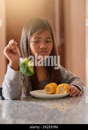 Warum werde ich wieder gefüttert. Kurzer Schuss eines kleinen Mädchens, das sich weigert, ihren Brokkoli zu essen. Stockfoto