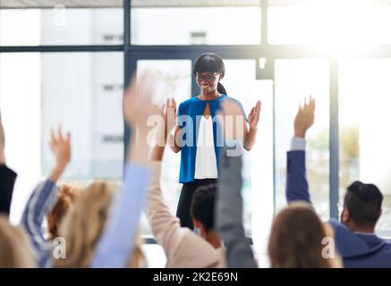 Führen und Lernen. Ausgeschnittene Aufnahme einer Gruppe von Menschen, die in einer Klasse die Hände heben. Stockfoto