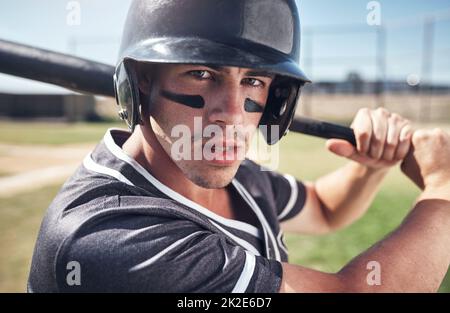 Kein Platz für mittelmäßig hier. Aufnahme eines jungen Mannes, der bei einem Baseballspiel seinen Schläger schwingt. Stockfoto