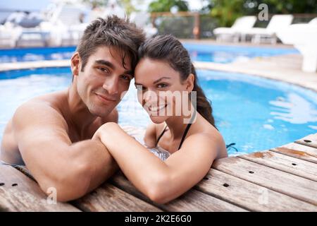 Köpfe und Herzen zusammen. Porträt eines attraktiven jungen Paares, das sich in einem Pool entspannt. Stockfoto