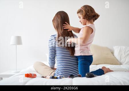 Ich wünschte, ich hätte lange Haare wie du, Mama. Aufnahme eines kleinen Mädchens, das sich im Schlafzimmer die Haare ihrer Mutter putzt. Stockfoto