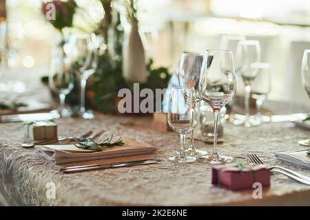 Die Tischeinstellung sieht auf Punkt aus. Aufnahme eines schön gedeckten Tisches mit Besteck und Geschirr, das tagsüber in einem Gebäude aufgestellt wurde. Stockfoto