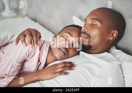 Liebe ist der süßeste Traum von allen. Aufnahme eines glücklichen jungen Paares, das zu Hause ein Nickerchen im Bett machte. Stockfoto