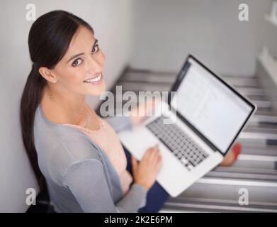 Vor dem Unterricht etwas Arbeit machen. Porträt einer jungen Frau, die mit einem Laptop auf einer Treppe sitzt. Stockfoto