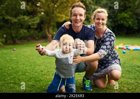 Spaß für die ganze Familie im Hinterhof. Aufnahme eines entzückenden kleinen Jungen und seiner Eltern, die im Hinterhof spielen. Stockfoto