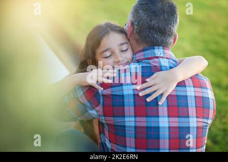 Daddys kleiner Liebling. Aufnahme eines glücklichen kleinen Mädchens, das ihren Vater zu Hause umarmt. Stockfoto