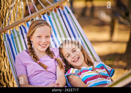 Einfach hängen. Aufnahme von zwei jungen Mädchen, die sich in einer Hängematte entspannen. Stockfoto