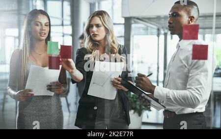 Ein Ziel, so viele Möglichkeiten, um dorthin zu gelangen. Aufnahme einer Gruppe junger Geschäftsleute, die in einem modernen Büro Brainstorming durchführen. Stockfoto