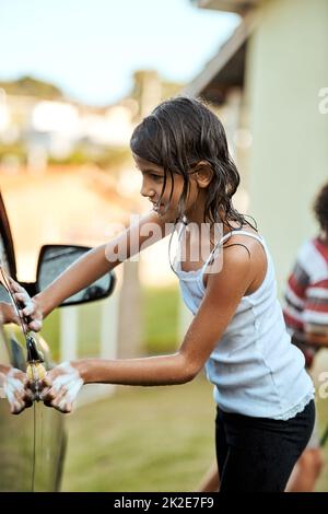 Ich muss sicherstellen, dass ich keinen Platz vermisse. Aufnahme eines fröhlichen kleinen Mädchens, das tagsüber das Auto ihrer Eltern wäscht. Stockfoto