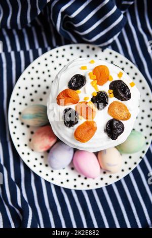 Ostereier und Osterkuchen liegen auf einem Teller auf einer gestreiften blauen Schürze. Das Konzept der Osterfeiertage. Stockfoto