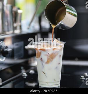 Der Barista bereitet einen köstlichen Eiskaffee mit Milch zu Stockfoto