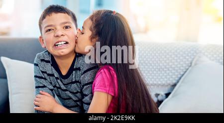 Igitt, Mädchen sind komisch. Aufnahme eines entzückenden kleinen Mädchens, das zu Hause ihren großen Bruder auf die Wange küsst. Stockfoto