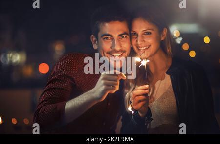 Unsere Liebe wird immer funkeln. Aufnahme eines glücklichen jungen Paares, das nachts mit Wunderkerzen gefeiert hat. Stockfoto