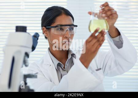 Konzentriert sich auf die Lösung medizinischer Geheimnisse. Ausgeschnittene Aufnahme einer jungen Wissenschaftlerin, die ein Experiment in einem Labor durchführt. Stockfoto