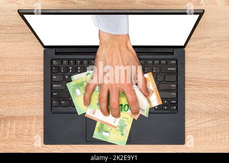 Hand greift aus dem Laptop-Bildschirm, um Geld zu stehlen Stockfoto