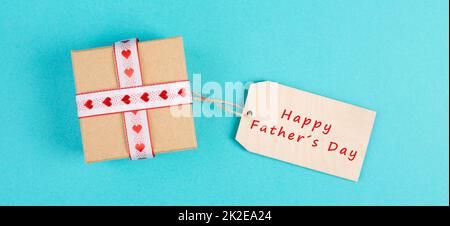 Kleine Geschenkbox mit Herzband auf blauem Hintergrund, Happy Fathers Day präsent Stockfoto