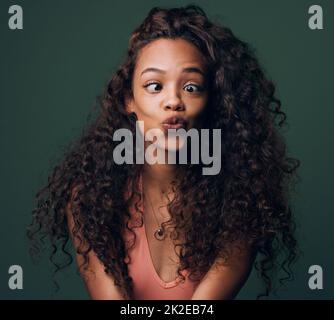 Pouting, weil ich hübsch bin. Eine kurze Aufnahme einer attraktiven und skurrilen jungen Frau, die vor grünem Hintergrund im Studio posiert. Stockfoto