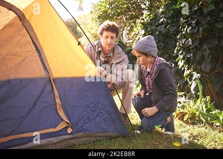 Es ist ein Durchgangsrecht. Ein Vater und sein kleiner Sohn stellen ihr Zelt auf. Stockfoto