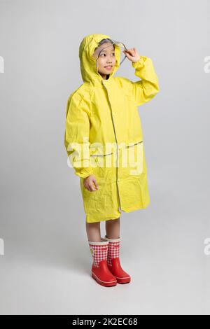 Nettes junges koreanisches Mädchen, Regenzeit Konzept im weißen Hintergrund Studio  tragen Regenmantel Stockfoto