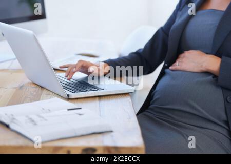 Arbeiten für die Zukunft der Babys. Zugeschnittenes Bild einer Schwangeren Geschäftsfrau, die im Büro an ihrem Laptop arbeitet. Stockfoto