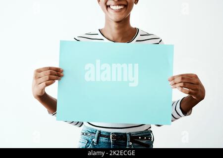 Nichts ergreift Aufmerksamkeit wie Farbe. Beschnittene Studioaufnahme einer Frau, die ein blaues Poster vor einem weißen Hintergrund hält. Stockfoto