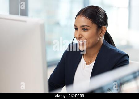 Sie besitzt alle Qualitäten eines Top-Vertriebsmitarbeiters. Aufnahme einer jungen Geschäftsfrau, die an einem Computer in einem Callcenter arbeitet. Stockfoto