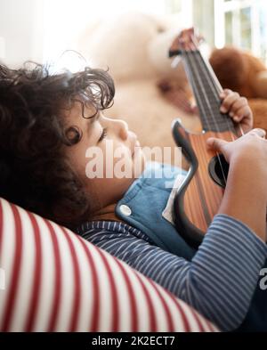 Für Träume zuschlagen. Aufnahme eines entzückenden Jungen, der mit einer Gitarre in seinem Schlafzimmer zu Hause spielt. Stockfoto