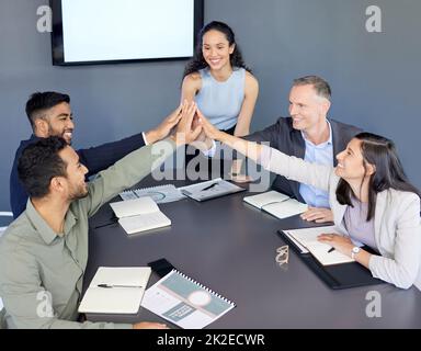 Würden dieses Projekt in den Ass nehmen. Aufnahme einer Gruppe von Geschäftsleuten, die sich während einer Besprechung in einem Büro gegenseitig eine hohe fünf gaben. Stockfoto