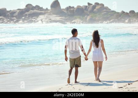 Halte meine Hand und lass sie nie los. Aufnahme eines jungen Paares, das einen Tag am Strand genießt. Stockfoto