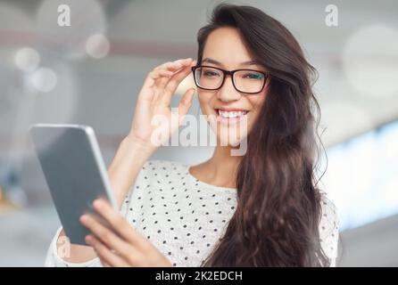 Immer und überall in Verbindung bleiben. Porträt einer attraktiven jungen Frau, die im Büro ein digitales Tablet nutzt. Stockfoto