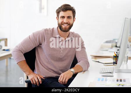 Ich bin definitiv in der richtigen Karriere. Porträt eines männlichen Designers, der an seinem Schreibtisch sitzt. Stockfoto