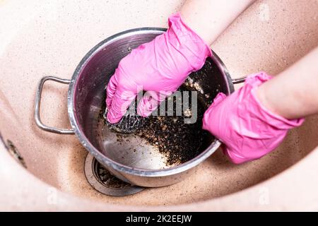 Waschen Sie die Pfanne mit verbranntem Essen und einem Metallschwamm Stockfoto