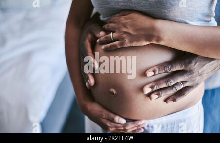 Diese Schwangerschaft gemeinsam durchgemacht haben. Kurzer Schuss eines unkenntlichen Mannes und seiner Frau, die ihren schwanger Bauch berührten. Stockfoto