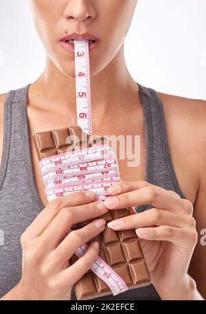 Shes ein Liebhaber von Schokolade. Studioaufnahme einer attraktiven jungen Frau, die von etwas Süßem verlockt wird. Stockfoto