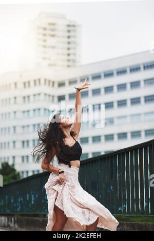 Tanzen erlaubt mir, mich völlig frei zu fühlen. Aufnahme einer attraktiven jungen Frau, die in der Stadt tanzt. Stockfoto