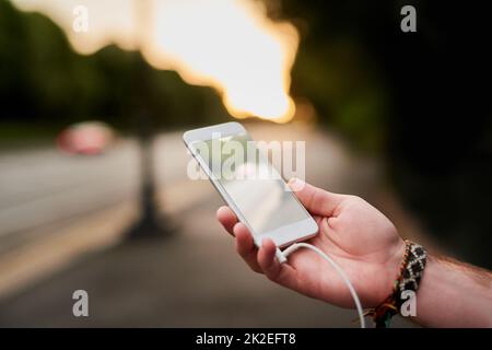 Musik ist der beste Reisebegleiter. Eine Aufnahme eines unverkennbaren Mannes, der auf seinem Handy Musik hört, während er durch die Stadt läuft. Stockfoto