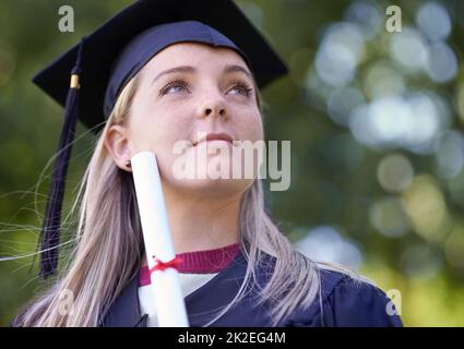 An ihre Zukunft denken. Eine Absolventin, die ihr Diplom hält. Stockfoto