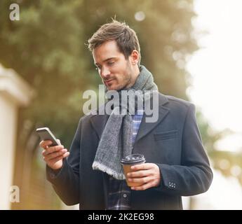 Bleiben Sie unterwegs auf dem Wissenswerte. Aufnahme eines jungen Mannes, der sein Telefon draußen benutzte. Stockfoto