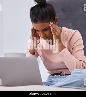 Was werde ich tun. Kurze Aufnahme einer attraktiven jungen Frau, die gestresst aussieht, während sie im Schlafzimmer zu Hause an ihrem Laptop arbeitet. Stockfoto