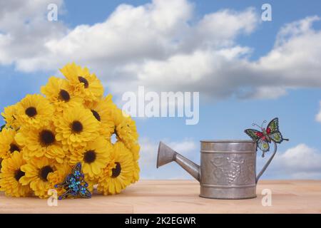 Gelbe Blumen und Metall-Wasser kann mit Blue Sky Hintergrund Stockfoto