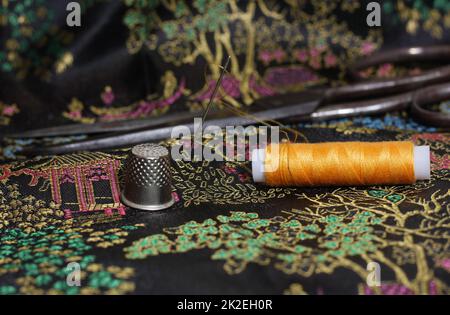 Gelbes Faden und Kaugummi auf klassischer chinesischer schwarzer Seide Stockfoto