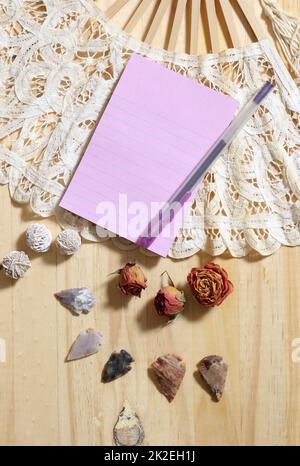 Notizbuch über Vintage-Spitzenfan mit getrockneten Rosen und indianischen Pfeilspitzen Stockfoto