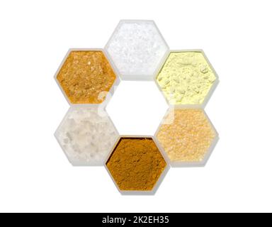 Chemischer Inhaltsstoff in hexagonalem molekularförmigem Behälter. Mikrokristallines Wachs, Schwefelpulver, Kandelillenwachs, Curcuma-Pulver, Flockensalz und Carnaubawachs Stockfoto