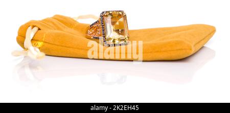 Citrin mit Ring aus blauem Saphir auf gelbem Samtbeutel. Kollektion von natürlichen Edelsteinen Accessoires. Studioaufnahme Stockfoto