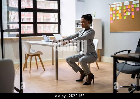 Eine Frau, Die Im Büro Yoga-Training Macht, Sitzt Auf Und Dehnt Sich Stockfoto