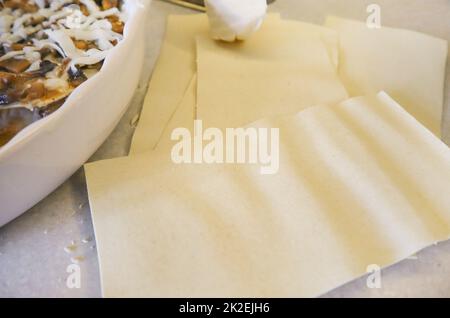 Traditionelle hausgemachte Lasagne. Lasagne-Platten IN DER NÄHE Einer RUNDEN KERAMIK-BACKFORM, Draufsicht Stockfoto