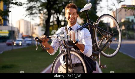 Denken Sie nur daran, wie viel Benzin Sie sparen. Aufnahme eines Geschäftsmannes, der mit seinem Fahrrad zur Arbeit pendelt. Stockfoto