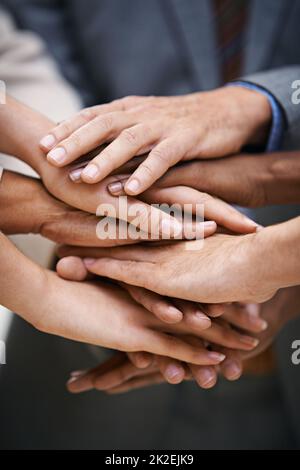 Wir geben unseren Erfolg von einem zum anderen. Aufnahme einer Gruppe von Geschäftsleuten, die ihre Hände in Einheit zusammenlegen. Stockfoto