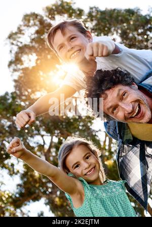 Die Erziehung seiner Kinder zu ihren eigenen Superhelden. Porträt eines glücklichen Vaters, der Zeit mit seinem Sohn und seiner Tochter im Freien verbringt. Stockfoto