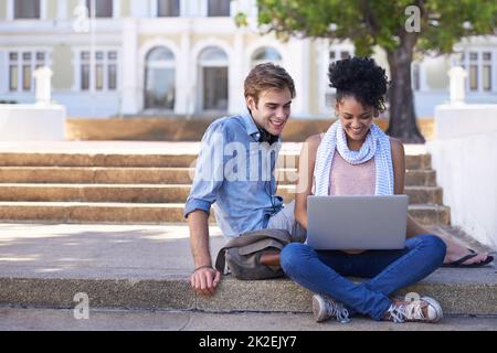 Bindung durch die Vorteile der Technologie. Aufnahme von zwei Studenten, die zusammen auf dem Campus studieren. Stockfoto